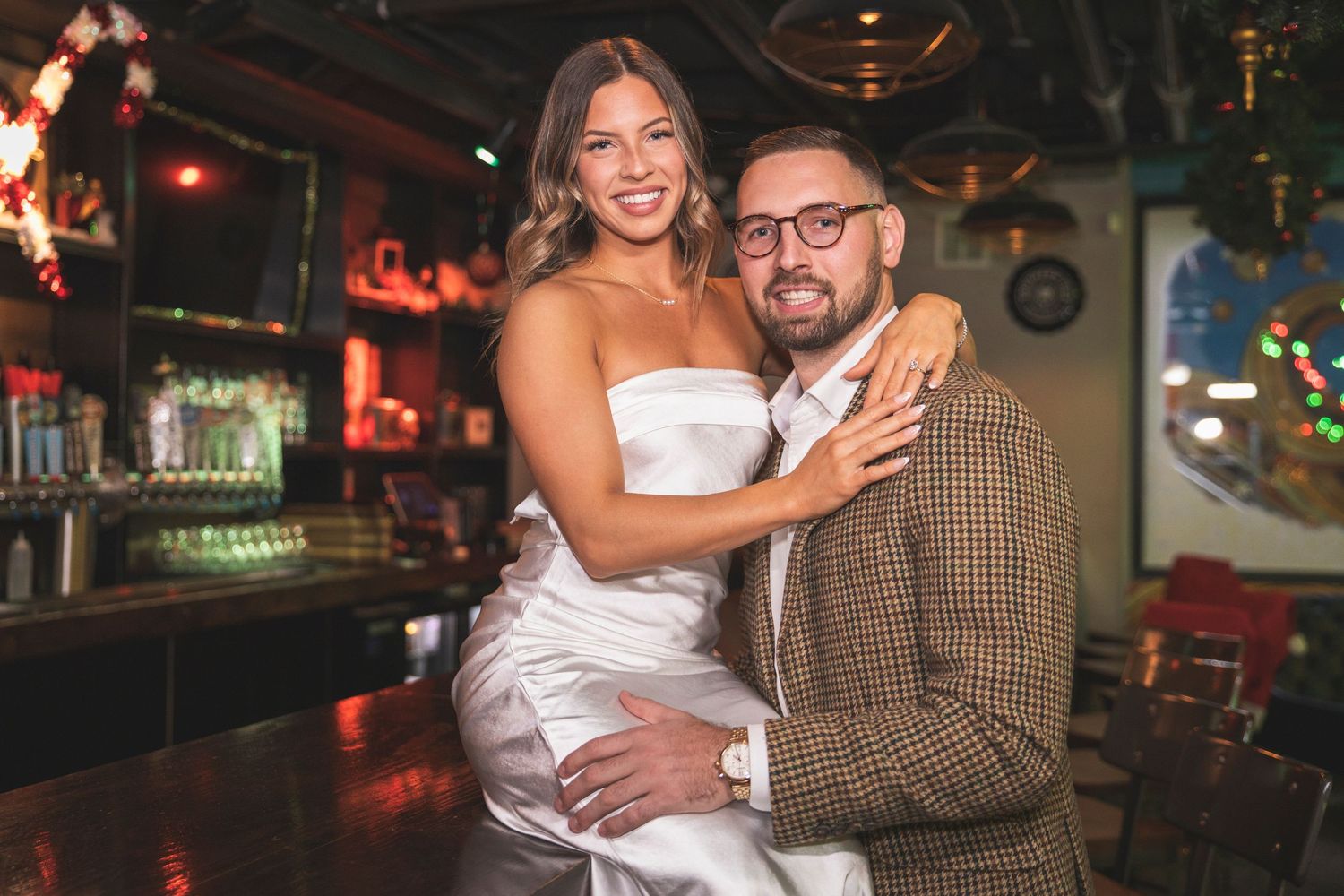 Nightlife scene showing a couple in formal attire enjoying drinks at an illuminated bar.