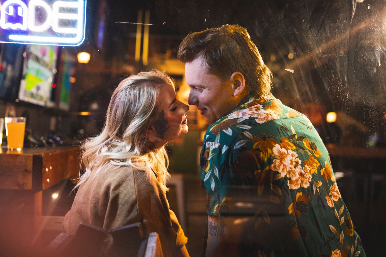 A couple celebrates at a dimly lit reception venue with colorful bokeh lighting in the background.