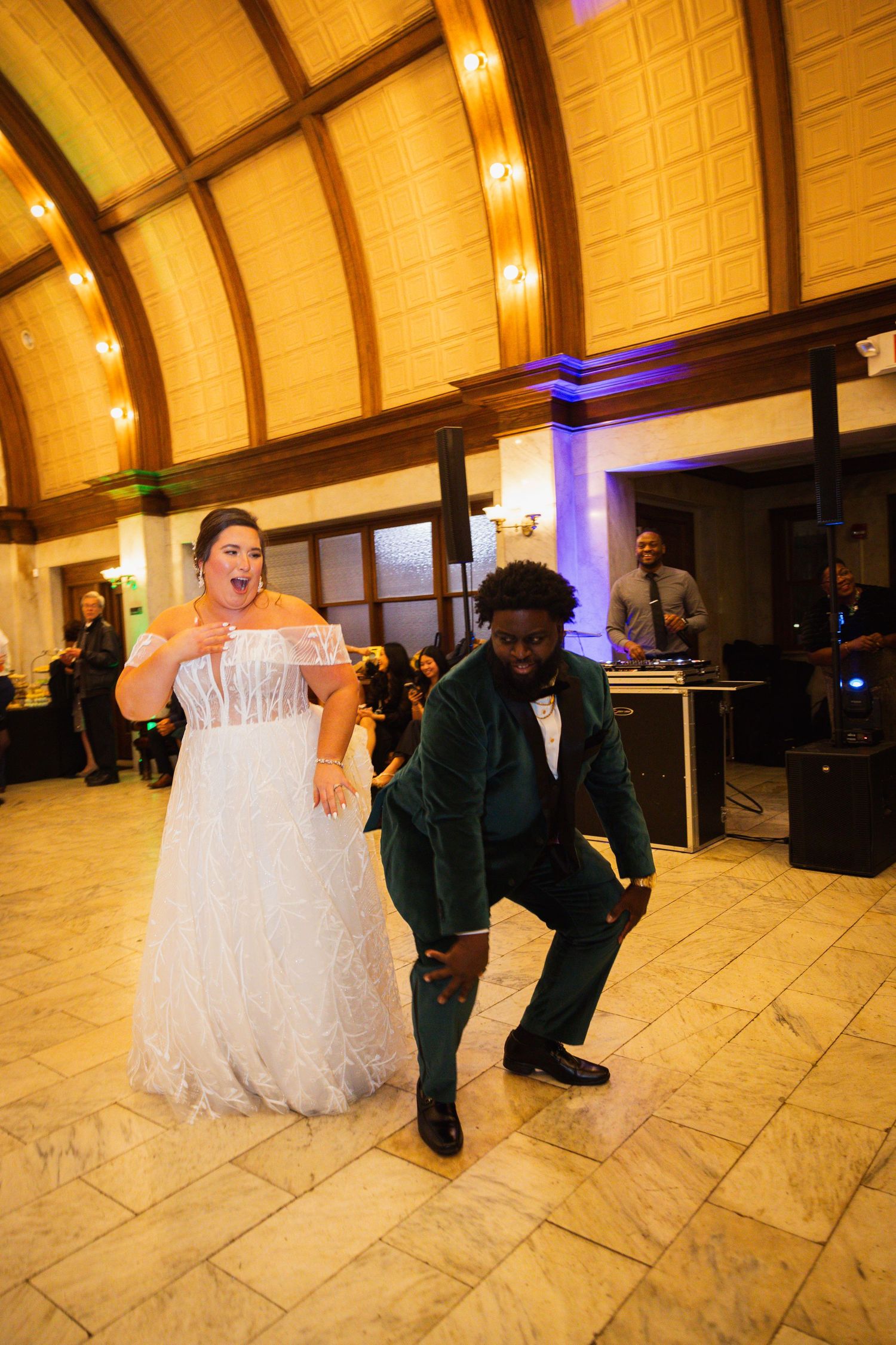 Wedding couple dances on marble floor under warm golden lighting at reception venue.