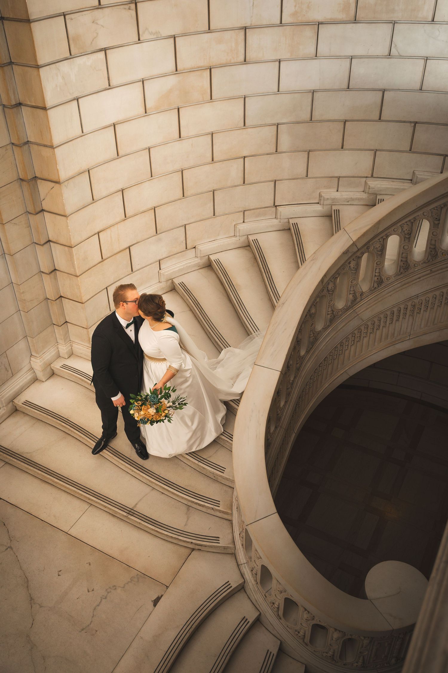 Spiral stone staircase with dramatic architectural lighting and archways in a historic building.