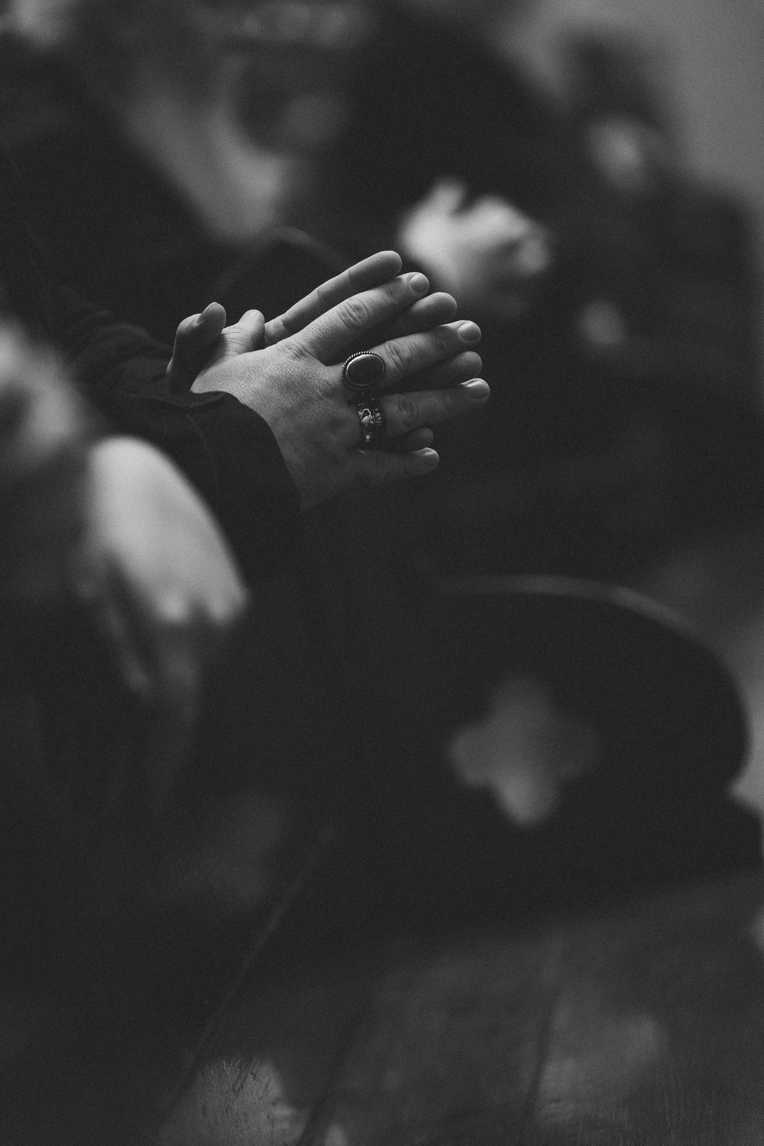 Black and white close-up of hands during an intimate moment at a wedding ceremony.