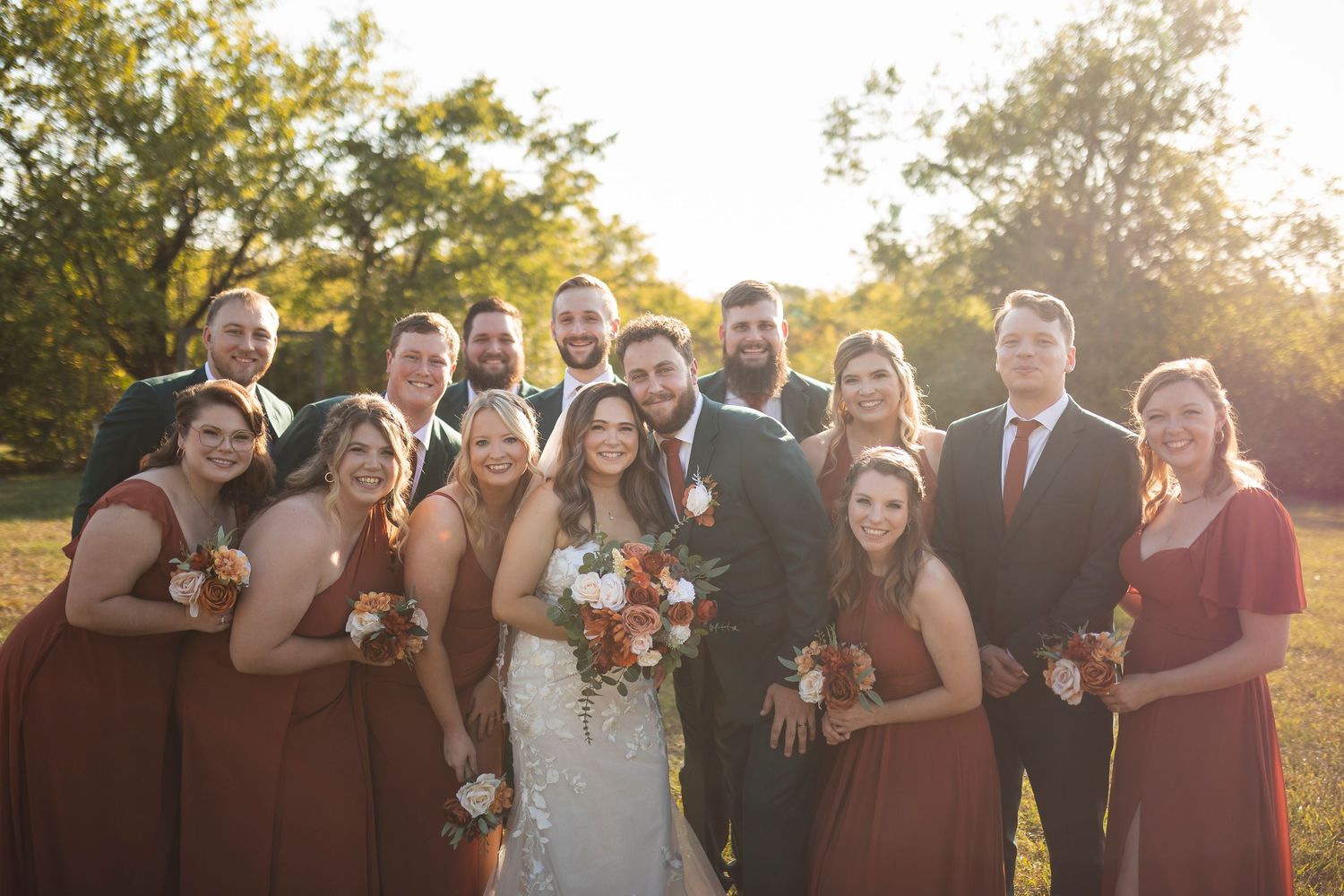 Wedding party group photo taken during golden hour with burgundy color theme.