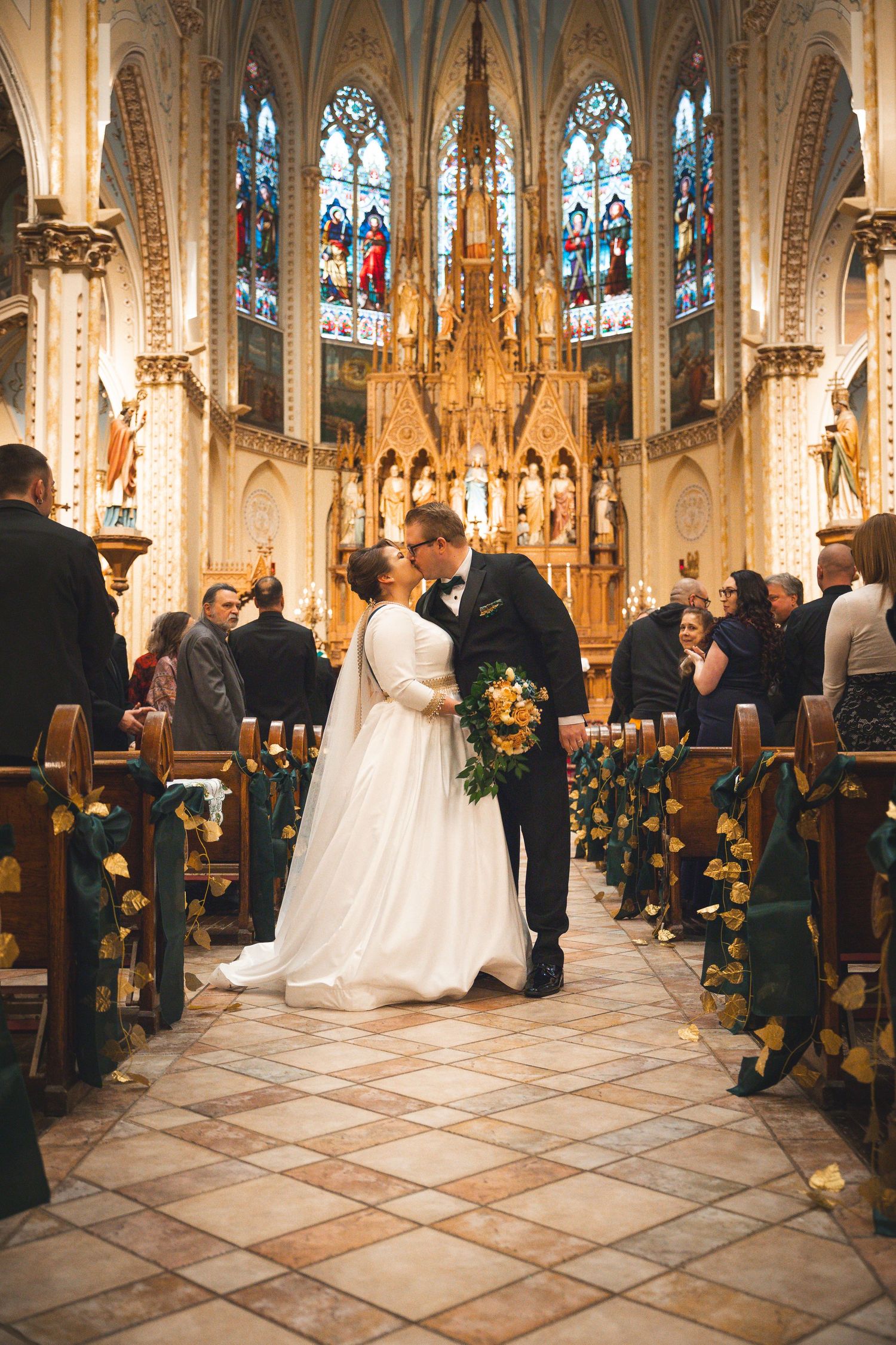 Gothic church interior decorated with yellow flowers and stained glass windows during a wedding ceremony.