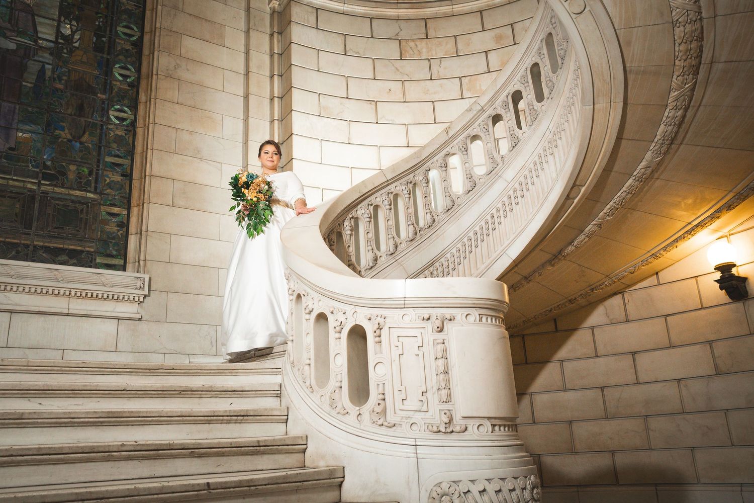 Ornate marble staircase with curved railings and architectural details in a grand building interior.