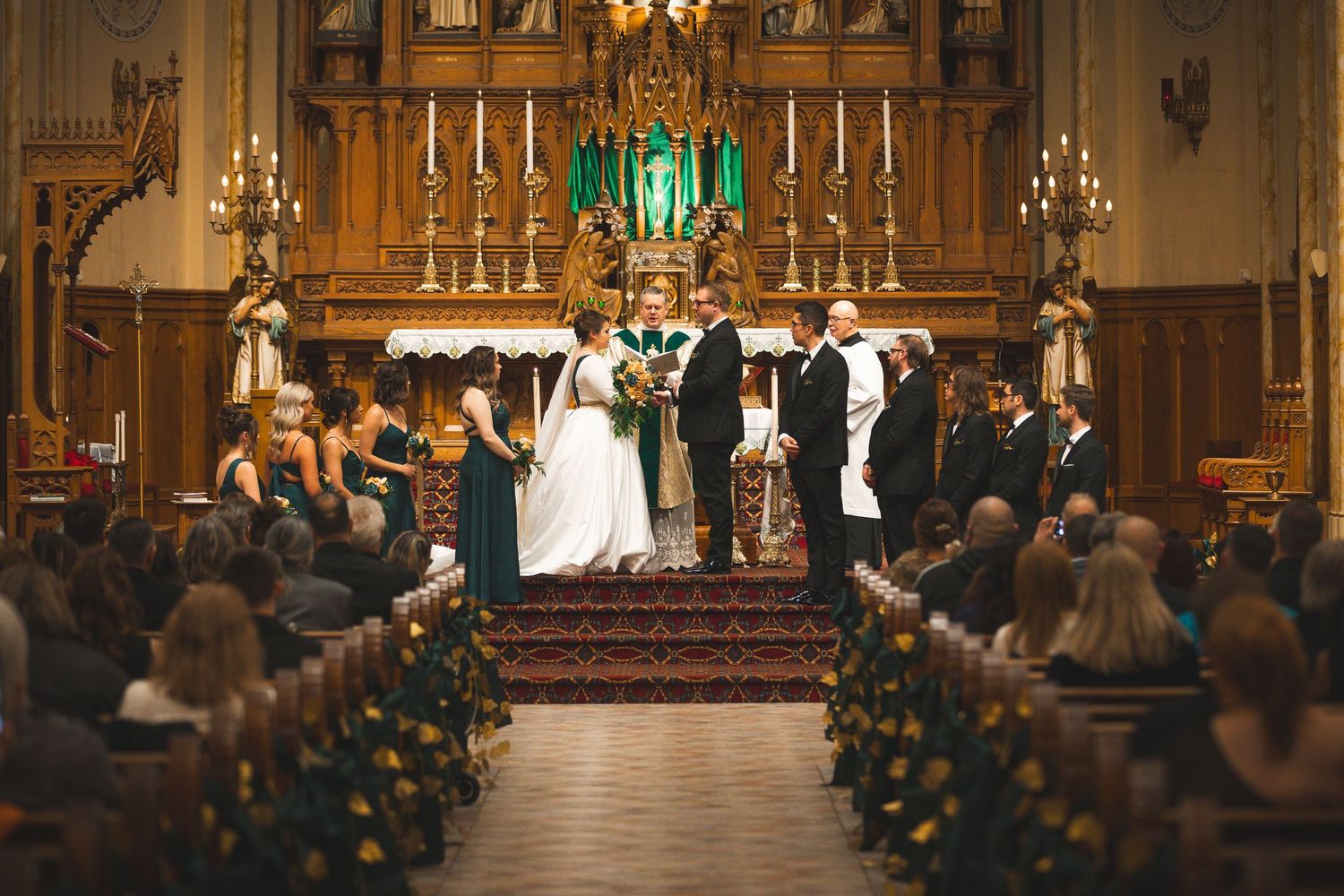 Panoramic view of a wedding ceremony in an ornate church sanctuary filled with guests.