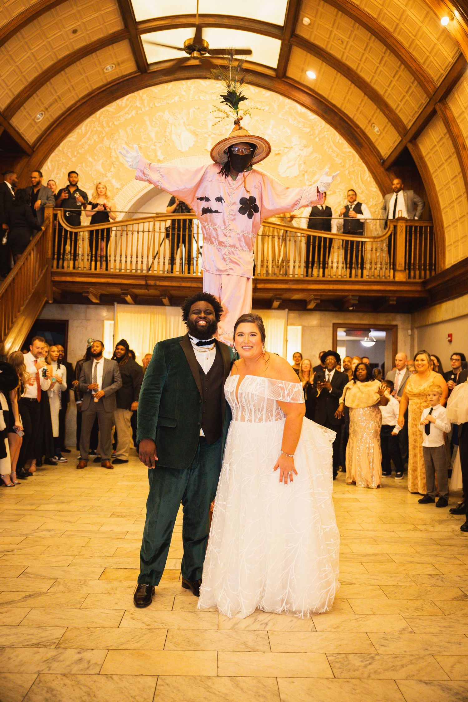 A wedding celebration unfolds on a spacious dance floor beneath an ornate vaulted ceiling with warm illumination.