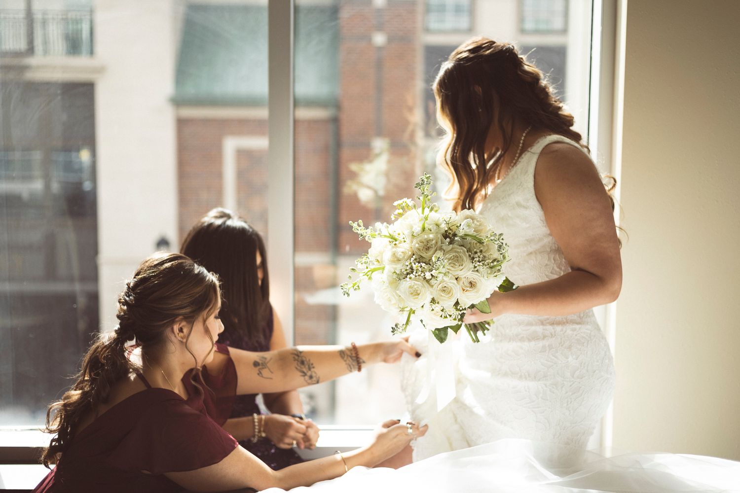 Soft window light illuminates a wedding day preparation scene indoors.