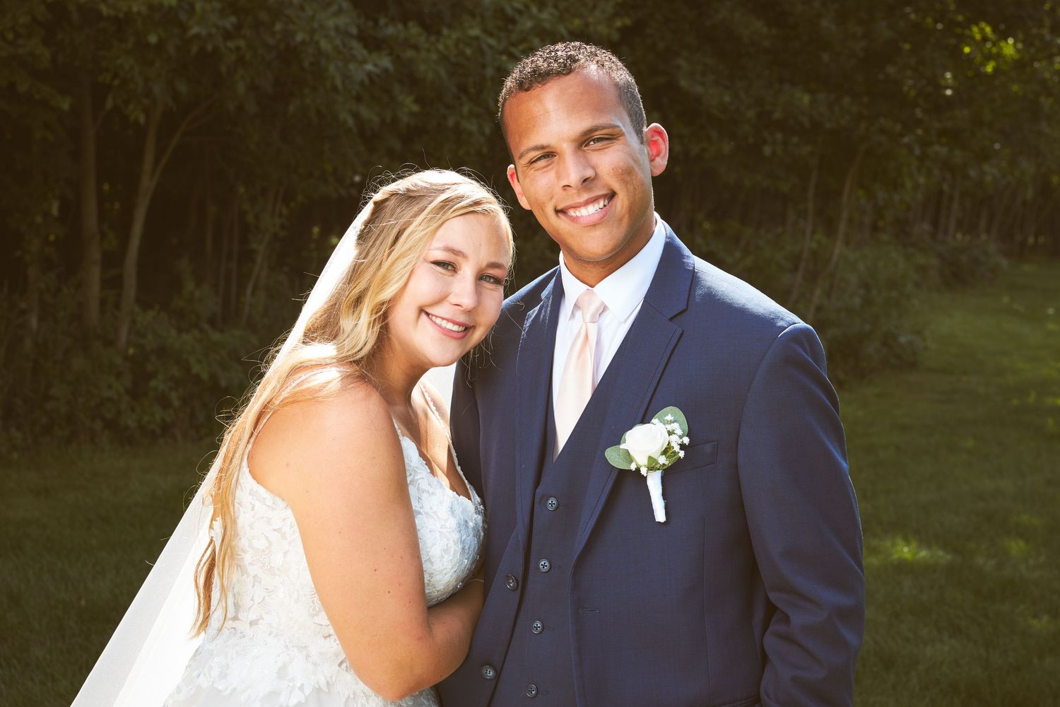 Wedding couple poses together outdoors in formal attire.