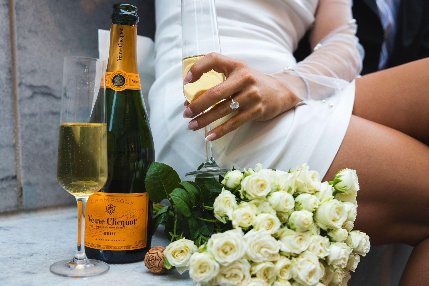 White roses and champagne bottles arrange elegantly for a wedding celebration.