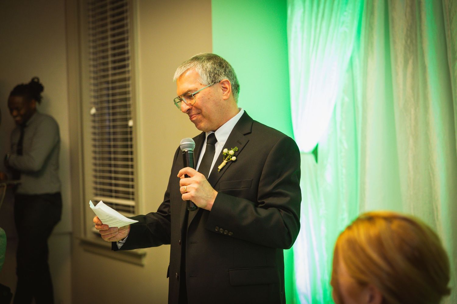 Formal event space with dramatic green lighting and white fabric backdrop.