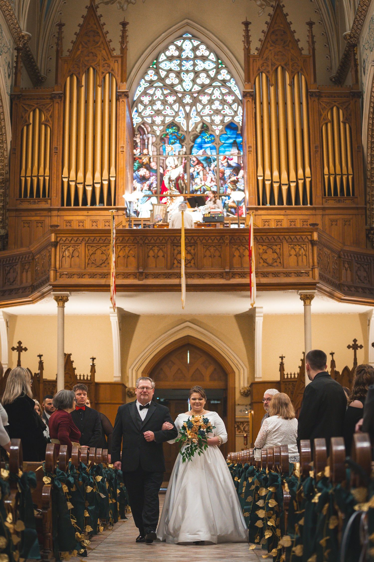 A wedding ceremony in a grand cathedral with golden organ pipes and stained glass windows.