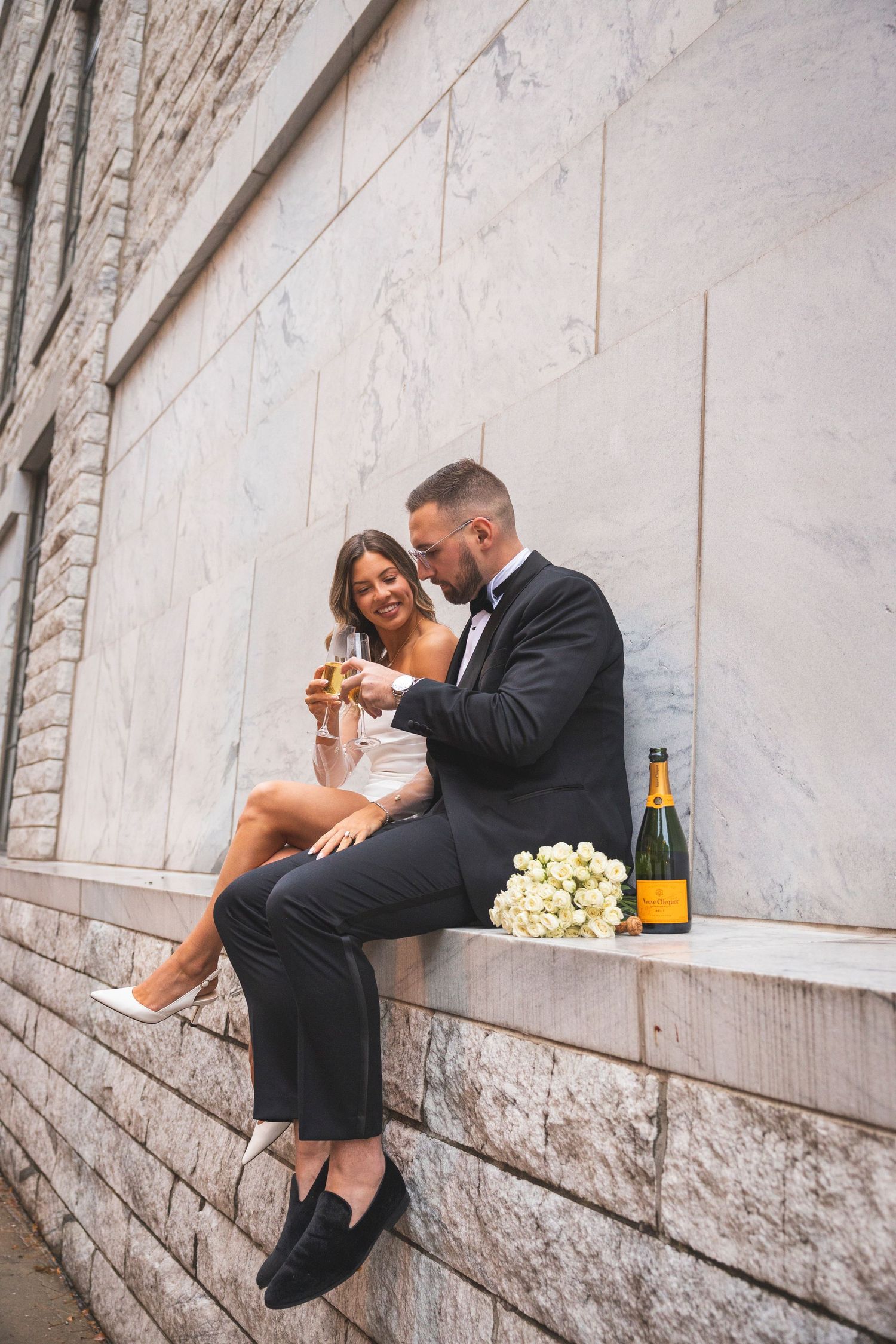 Romantic celebration with champagne and roses on stone ledge.