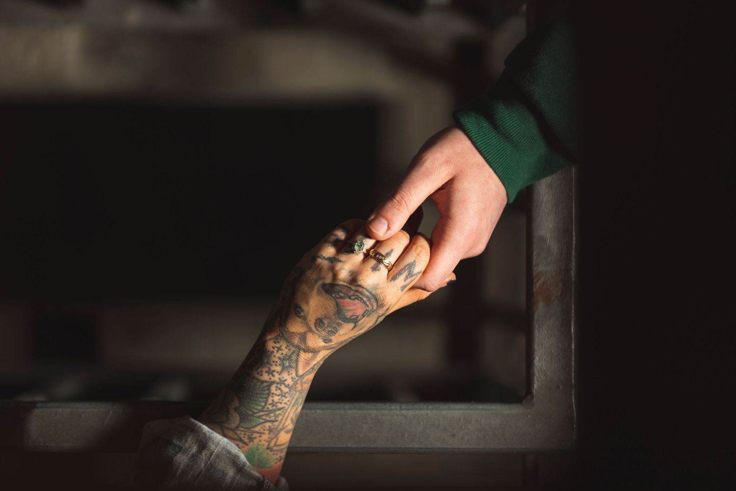 Close-up of hands with detailed tattoo artwork in dramatic lighting.