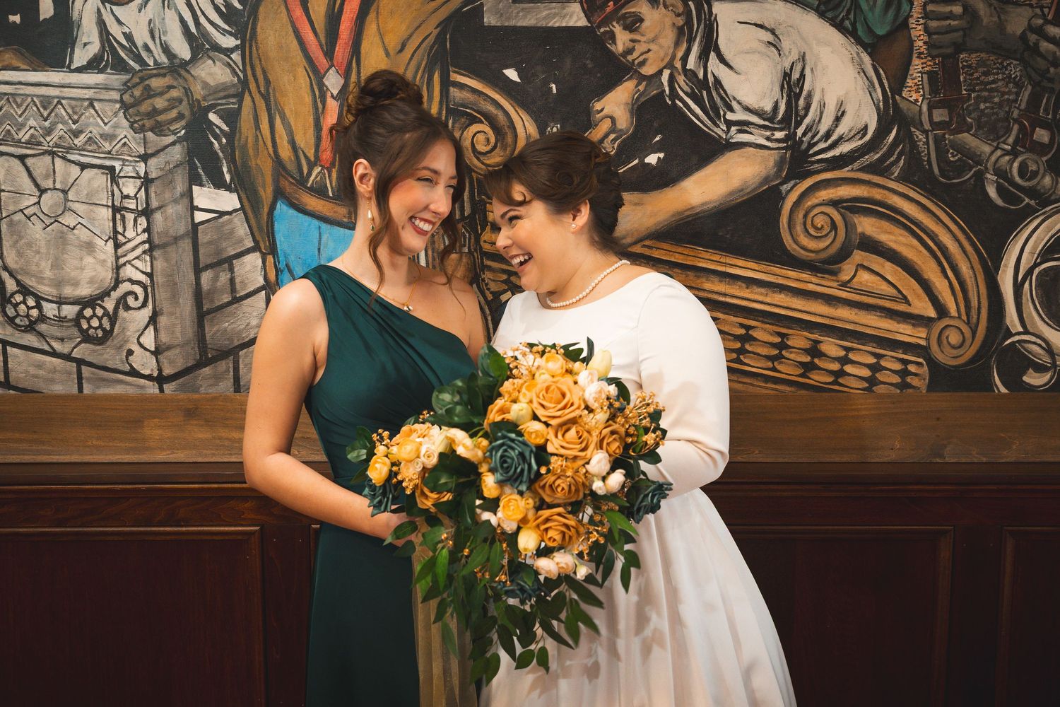 Wedding party members holding vibrant yellow and teal floral arrangements against dark wood paneling.