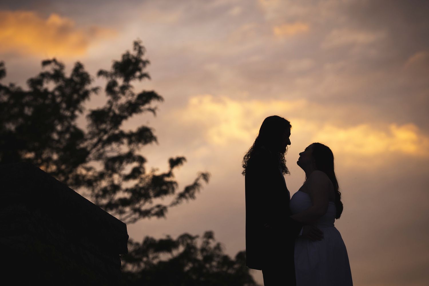 Two figures stand in silhouette against a dramatic sunset sky.