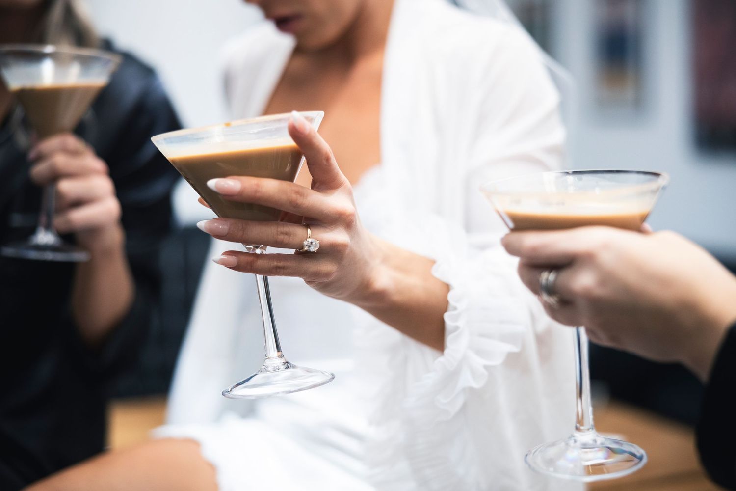 Elegantly dressed guests hold champagne flutes while mingling at a formal event.