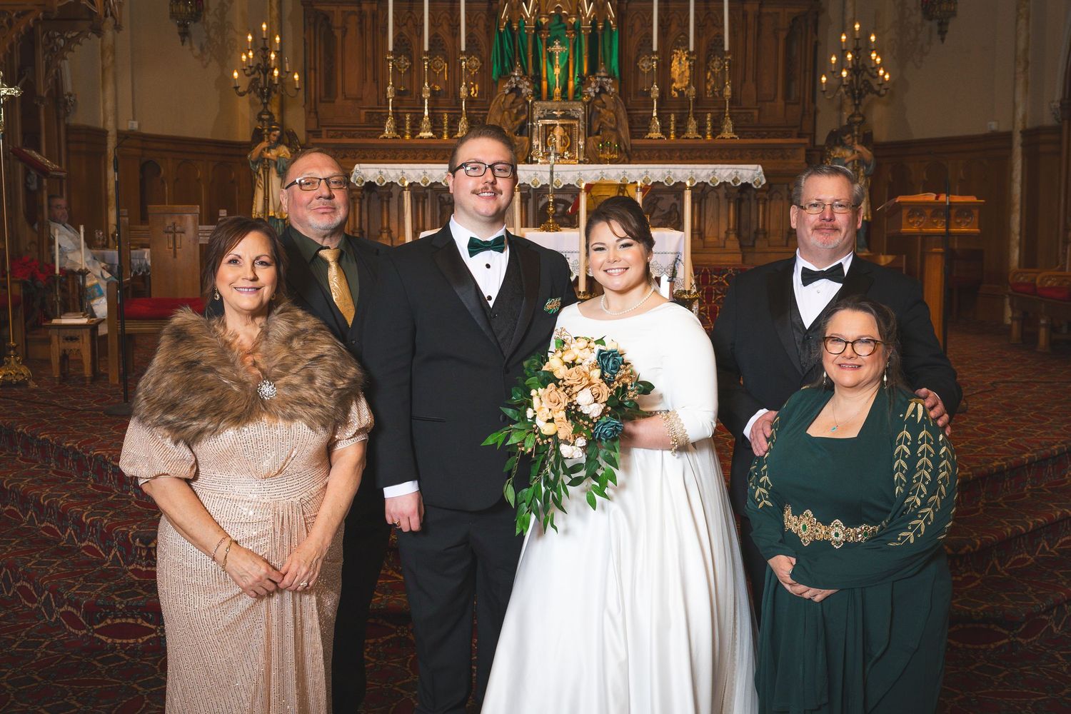 Wedding party members gathered in a historic church interior with ornate altar and decorations.