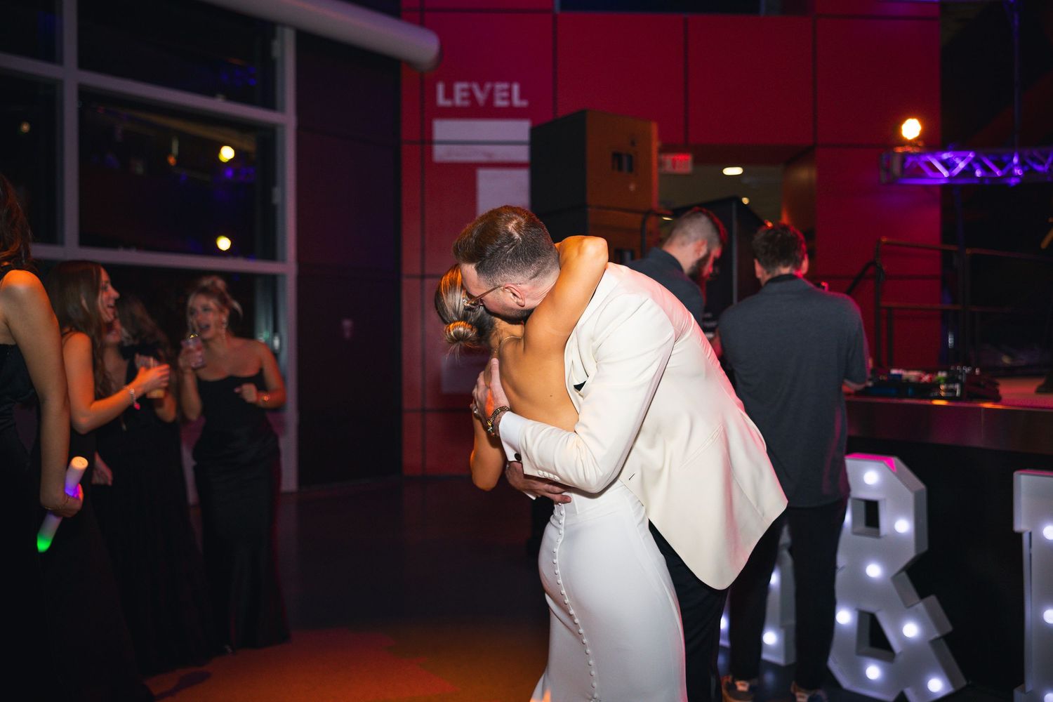 Wedding reception dance floor filled with guests under ambient lighting.