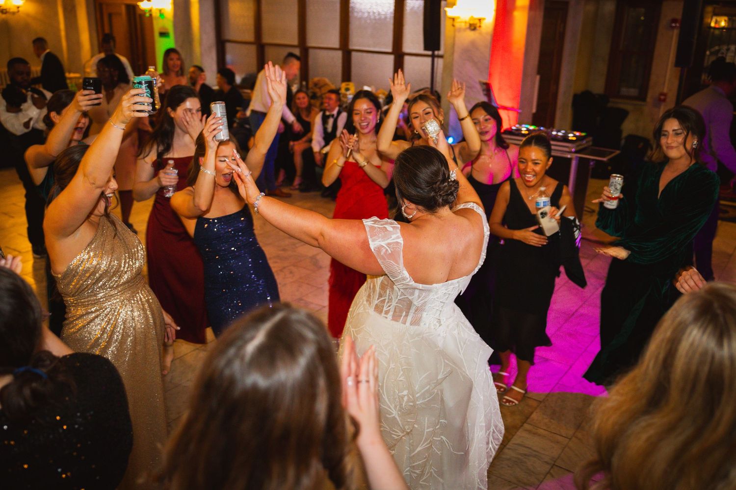 Energetic wedding reception dance party with colorful lighting and guests enjoying the celebration.
