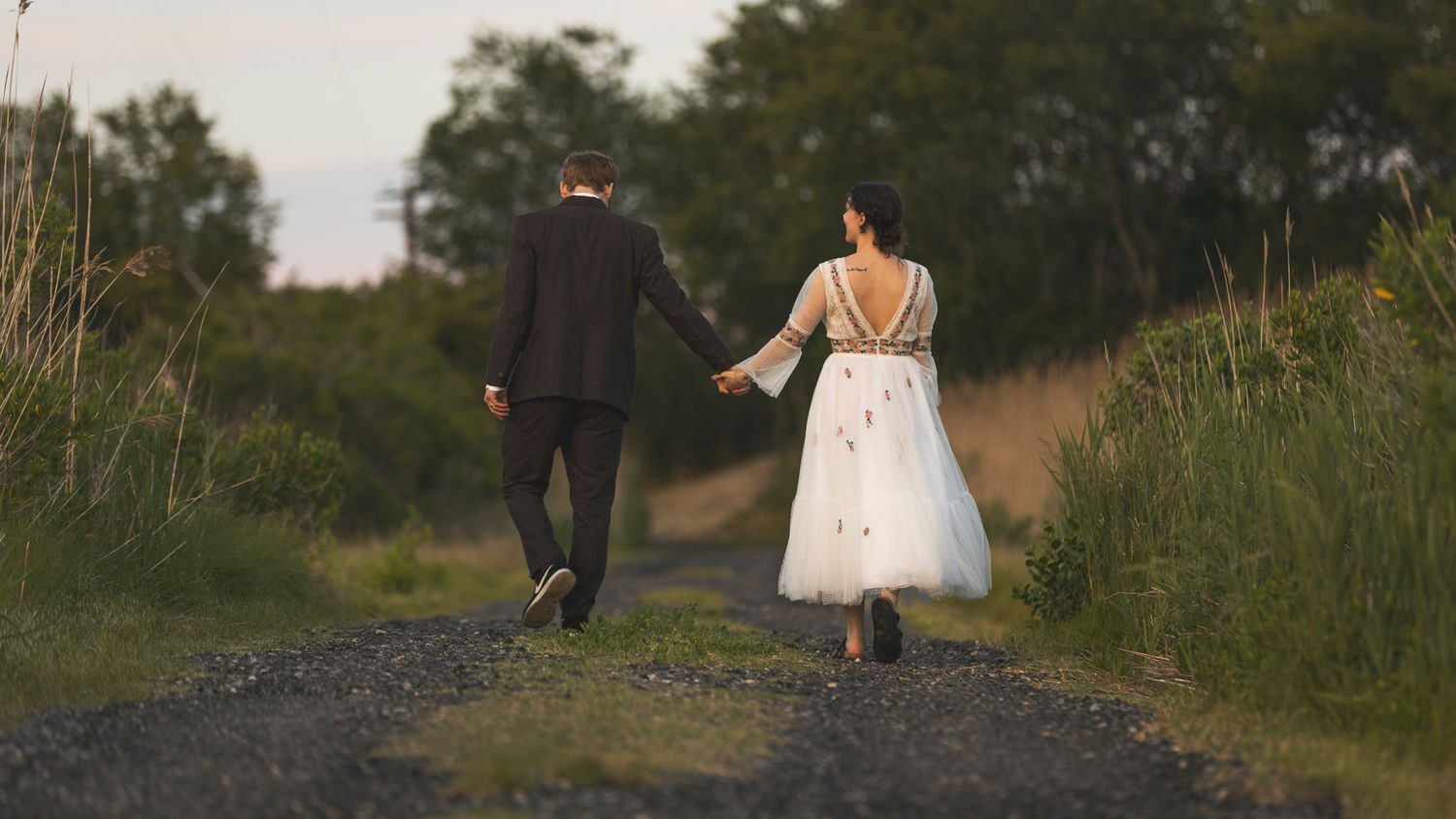 Couple walking along a natural path surrounded by summer greenery.