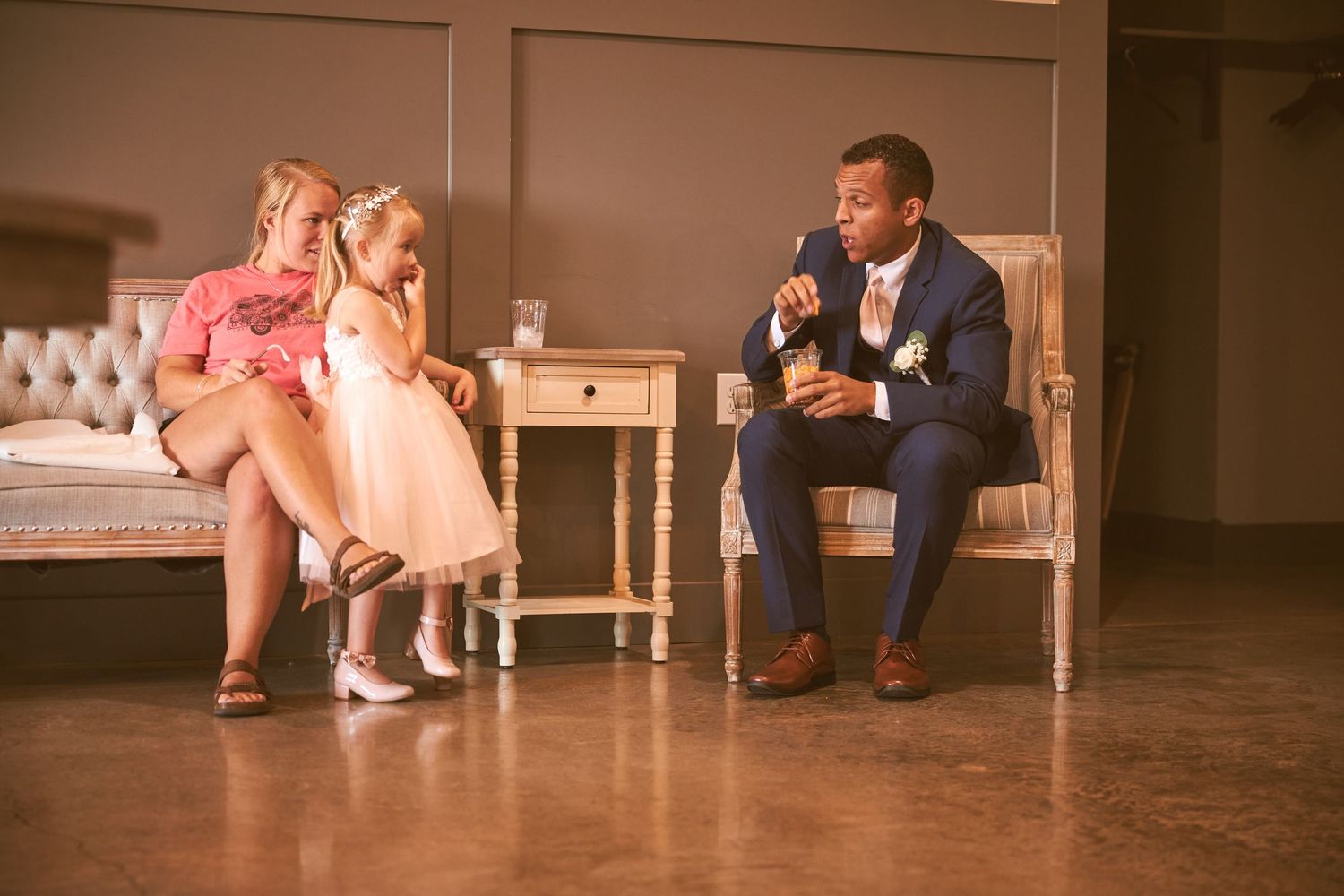 Sweet moment between wedding party members and young flower girls in pink dresses.