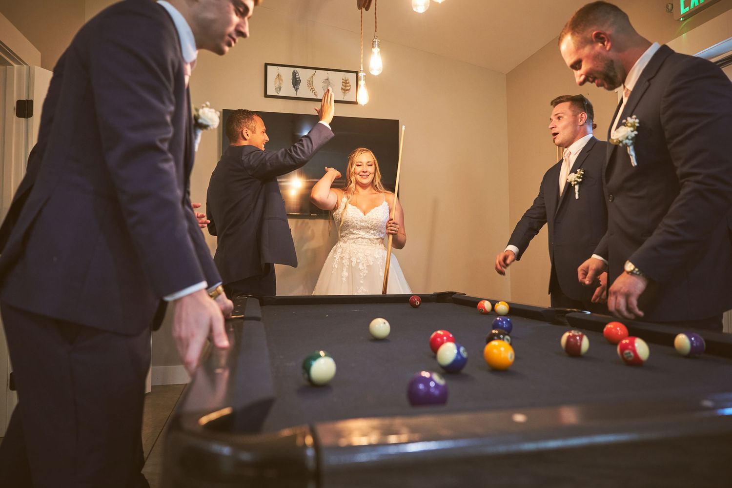 Wedding reception scene with people playing pool at an indoor venue.