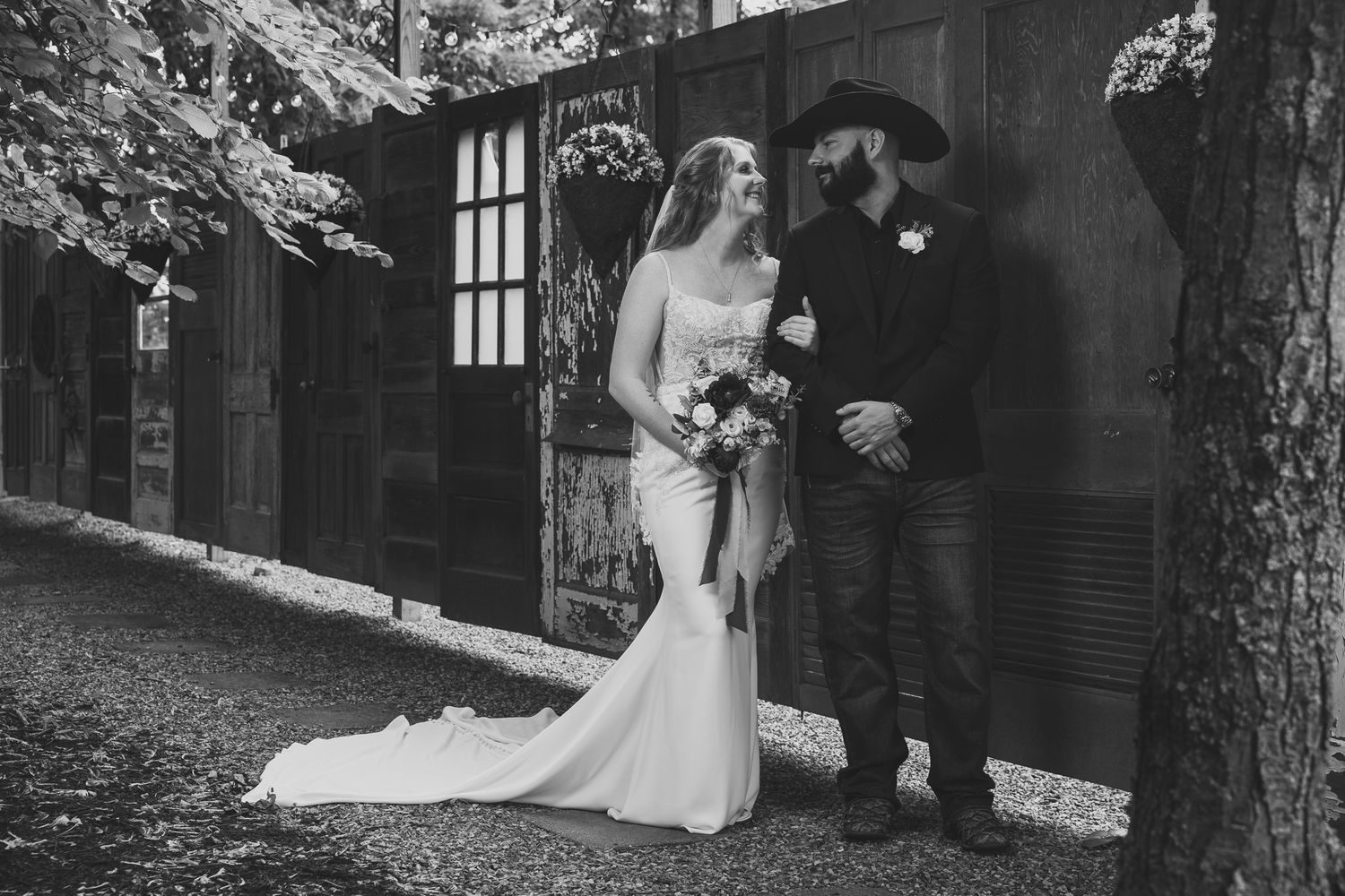 Wedding couple poses against rustic stone architecture in dramatic black and white photography.