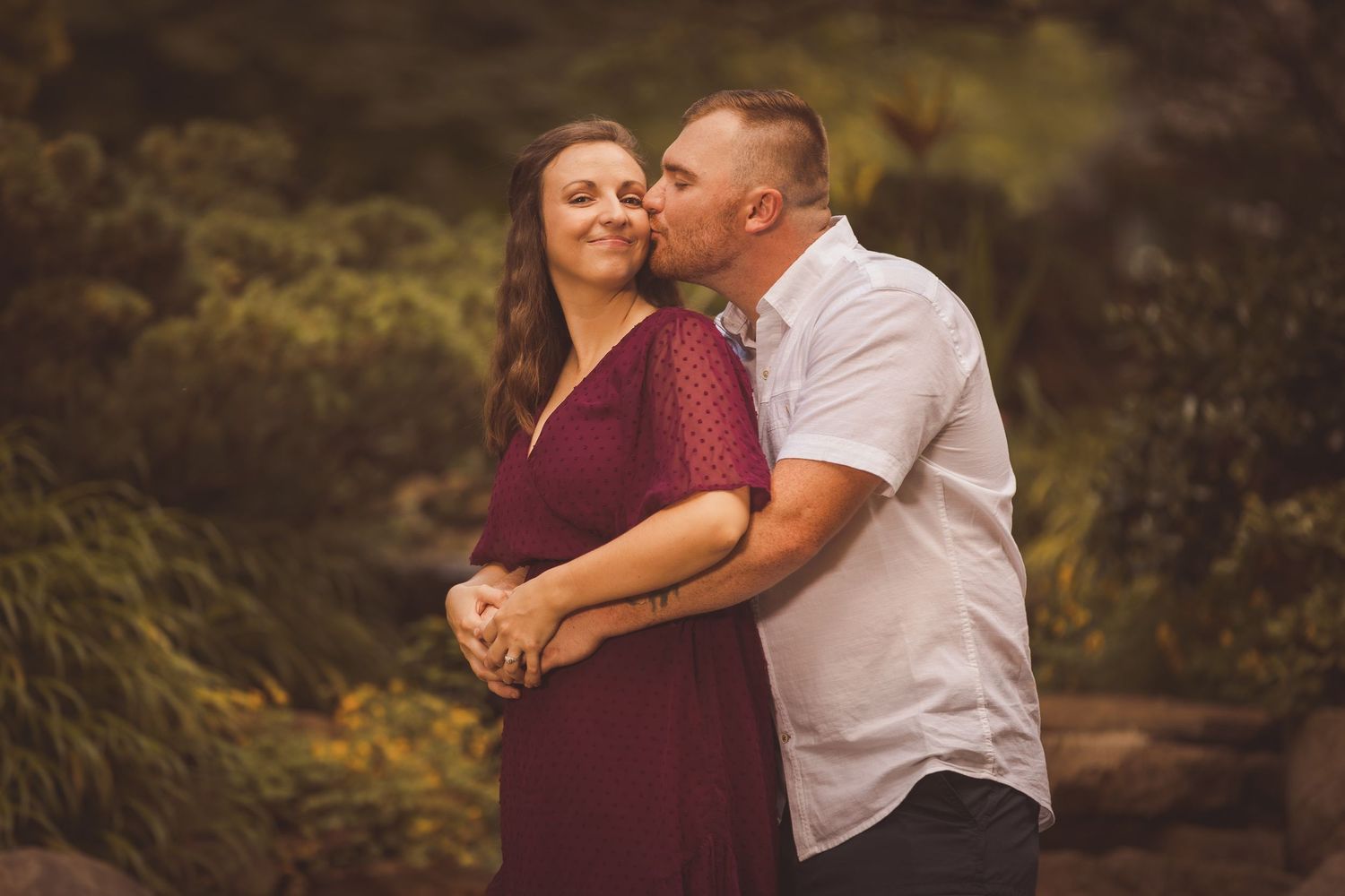 Intimate moment shared between couple against natural garden backdrop.