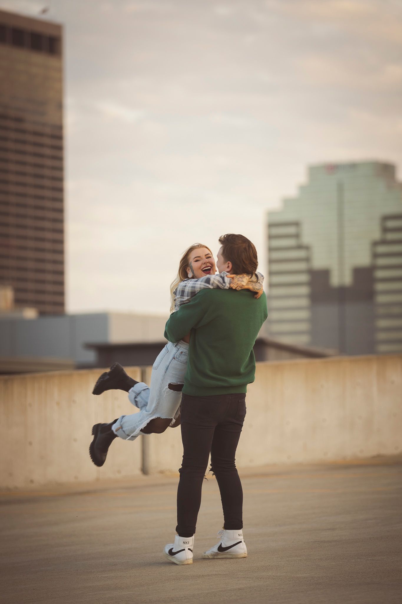 Joyful couple sharing playful moment on urban rooftop during sunset.