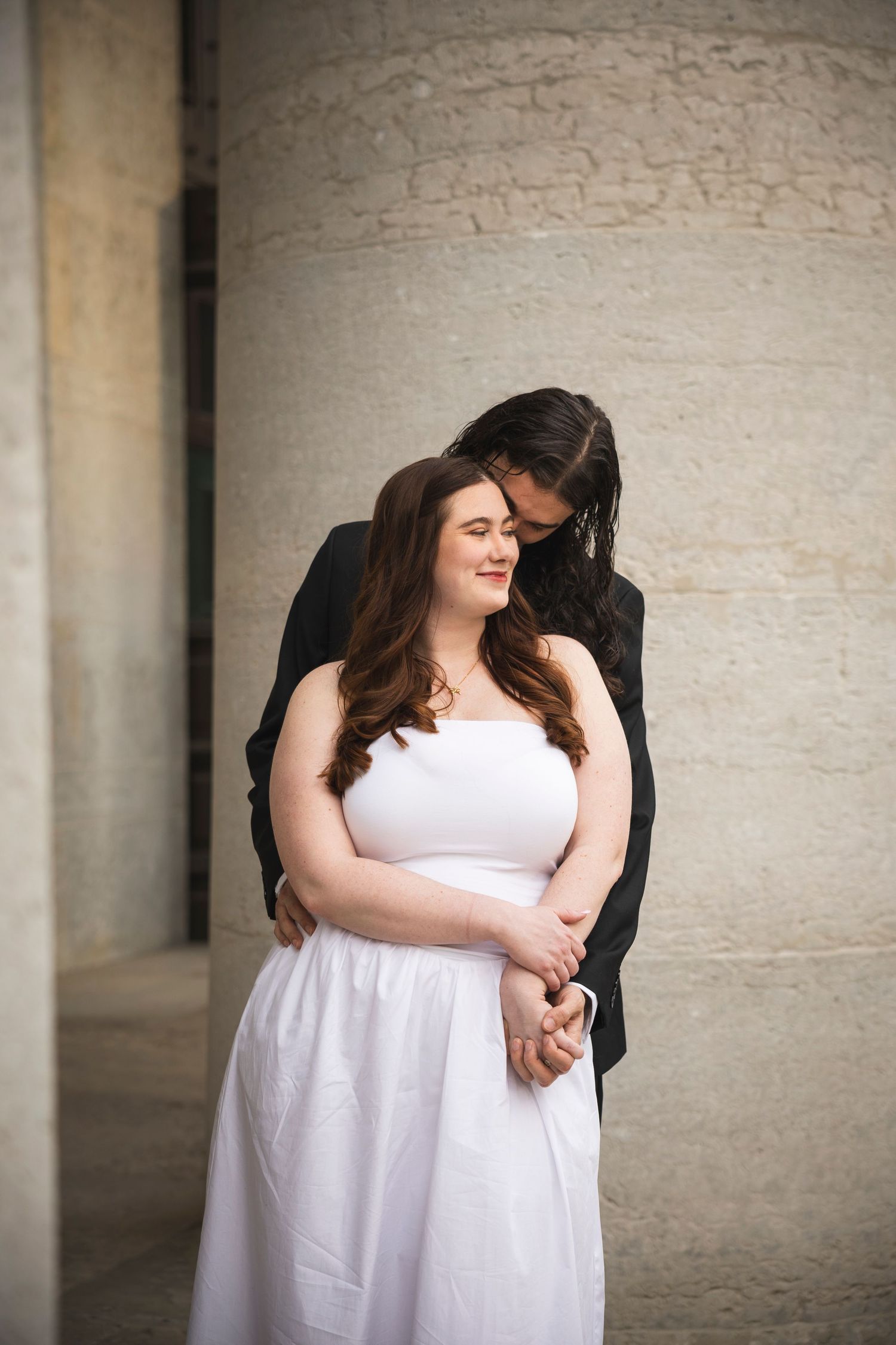 Intimate couple's portrait session showing tender moments against a textured wall background.