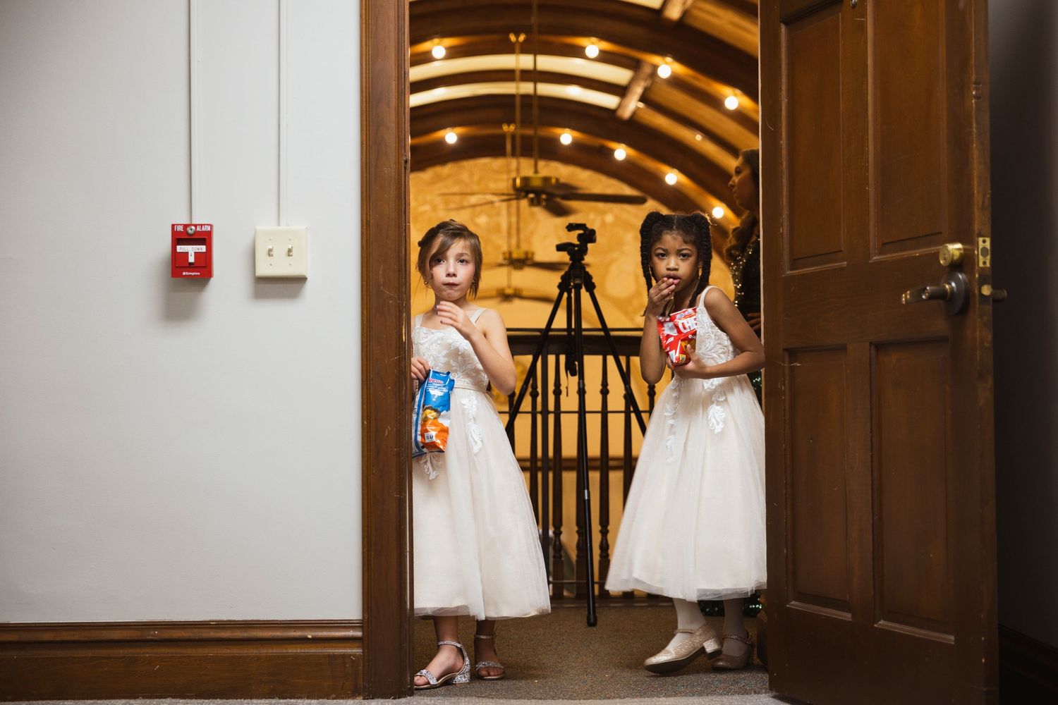 Wedding party members walking through an elegantly lit hallway in formal attire.