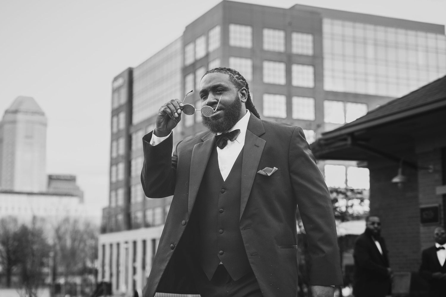 Person in formal wear captured in outdoor black and white portrait series against urban backdrop.