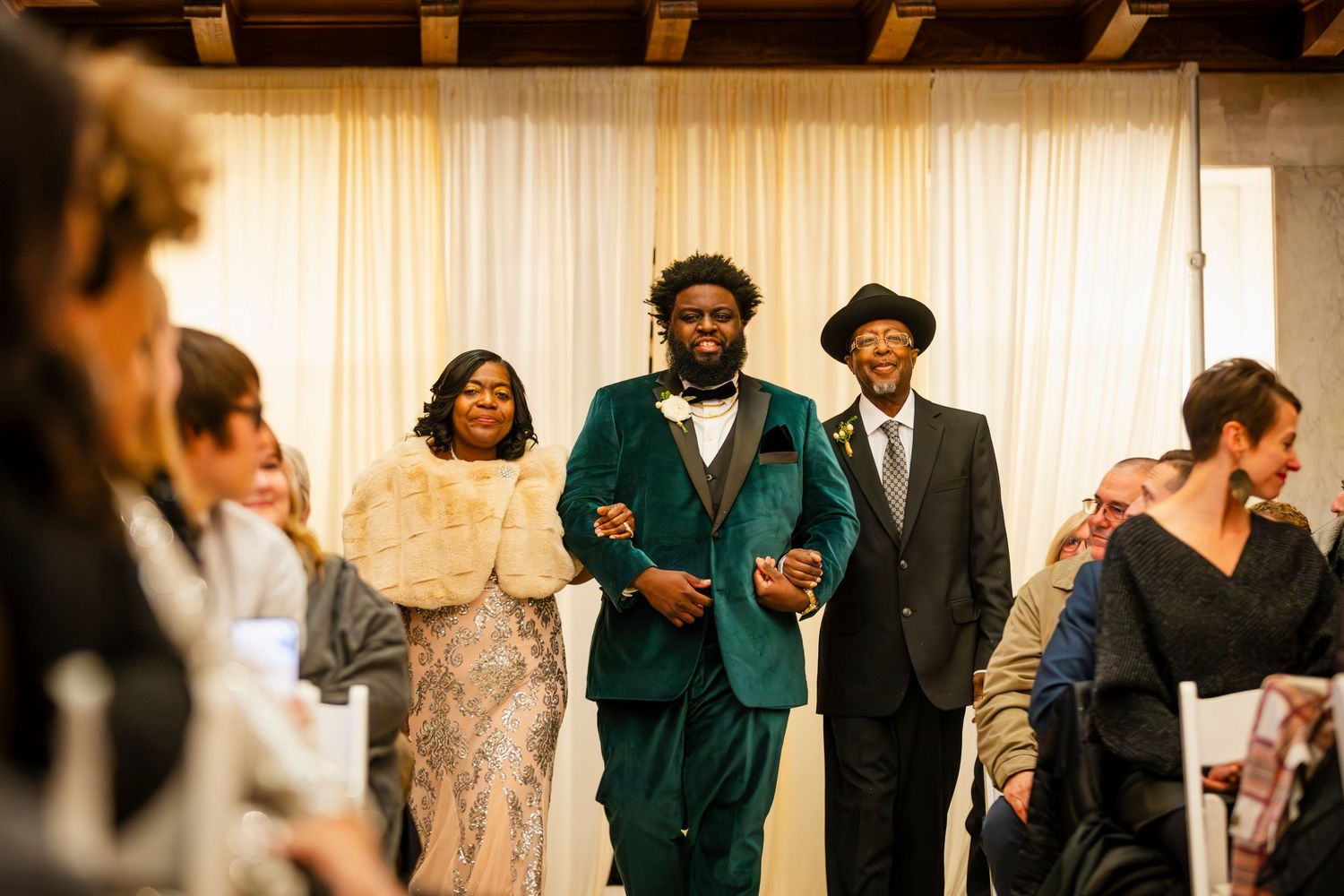 Elegant wedding reception scene with guests in formal attire celebrating in a warmly lit venue.