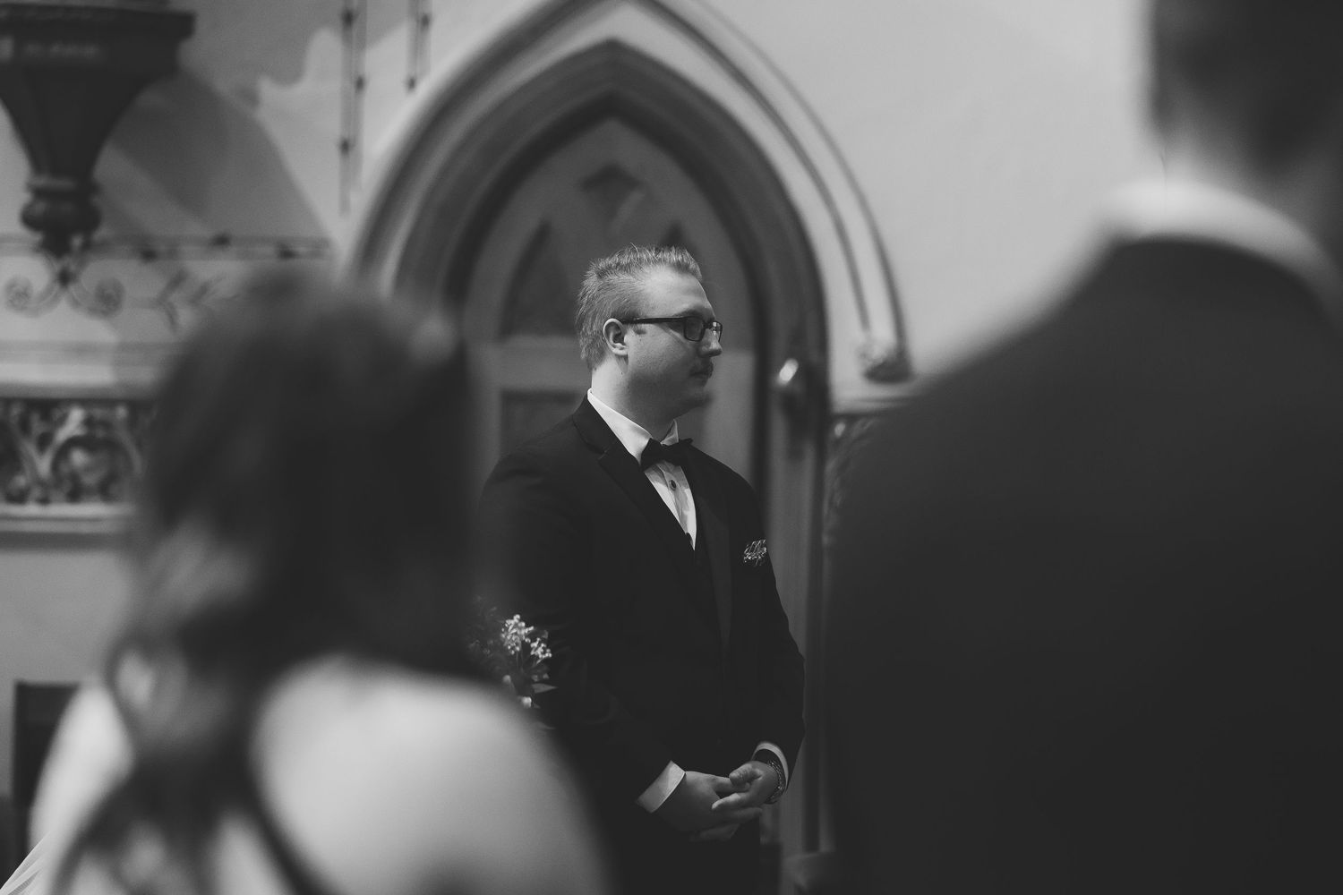 Wedding ceremony guests seated in dark wooden pews inside a gothic church.