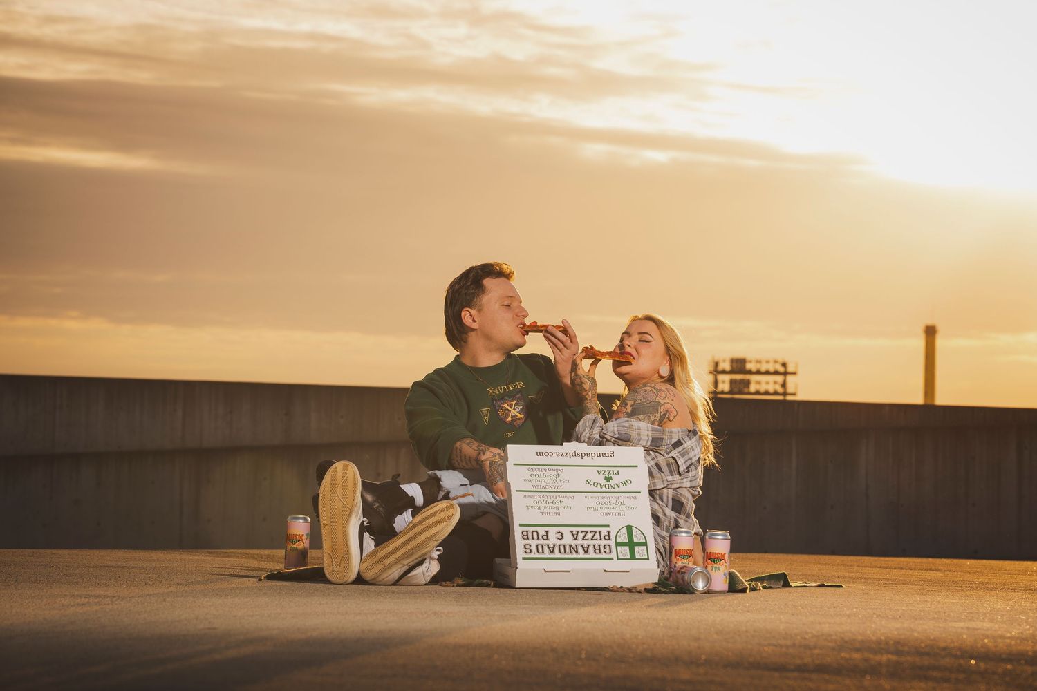 Couple enjoys a picnic on a rooftop during golden hour sunset.