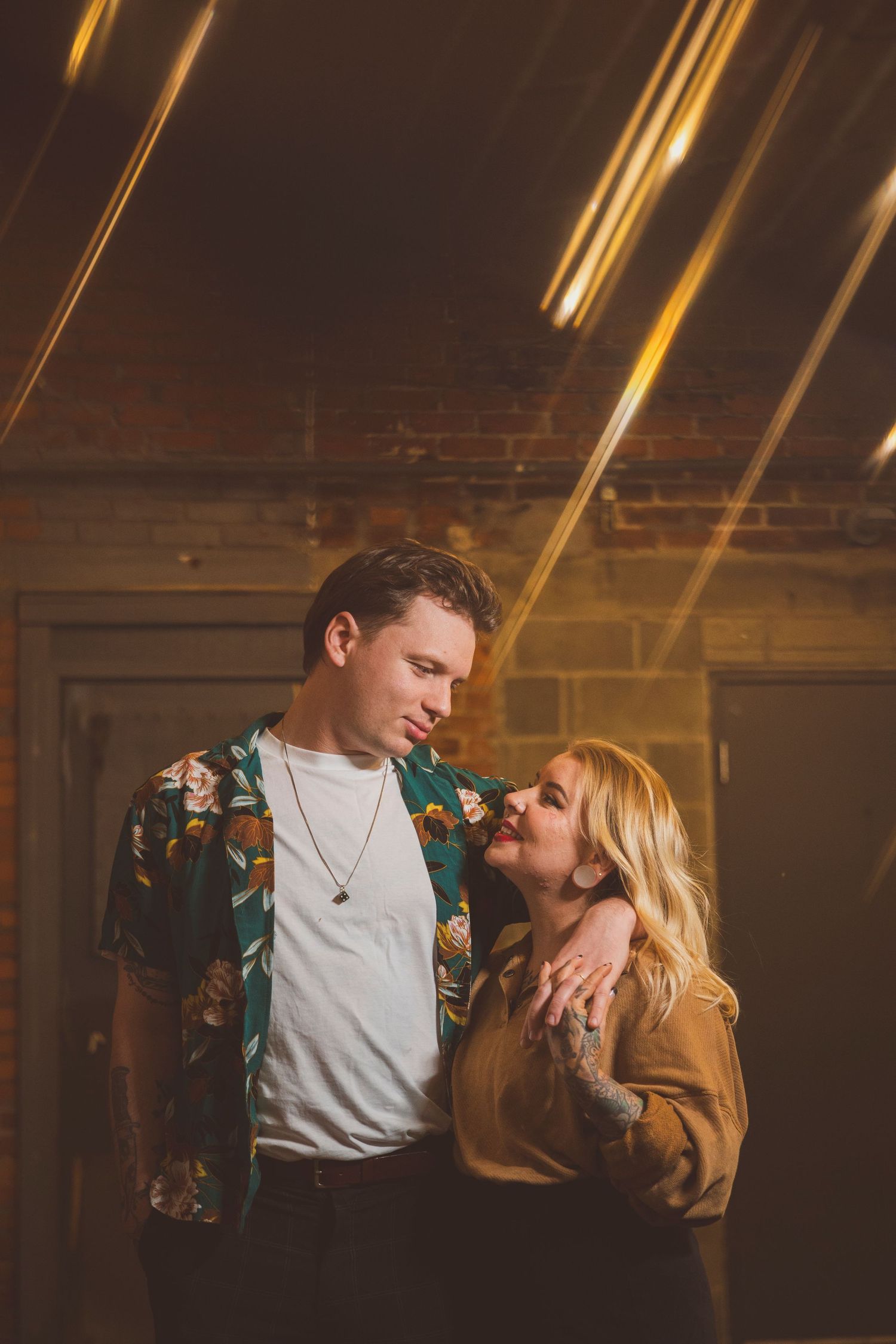 Couple in casual attire sharing intimate moment in dimly lit room.