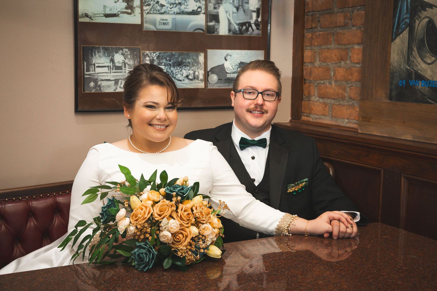A couple sits at a vintage booth with exposed brick walls and framed photographs.