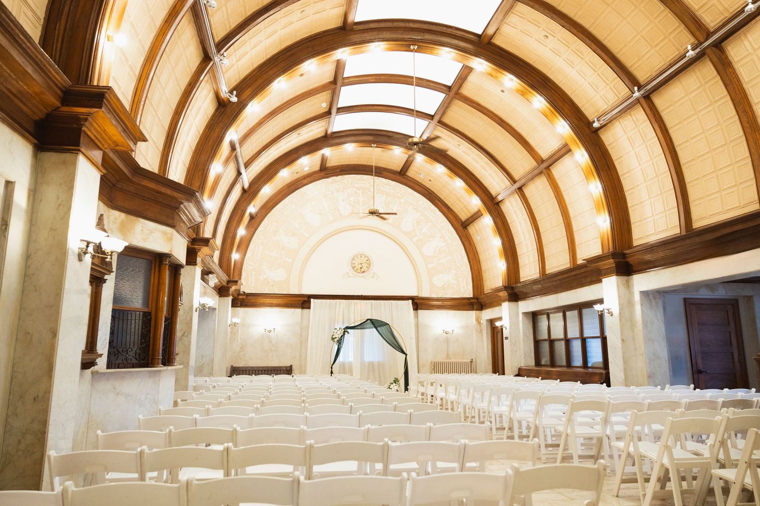 Panoramic view of an elegant church ceremony space with vaulted wooden ceiling and white chairs.