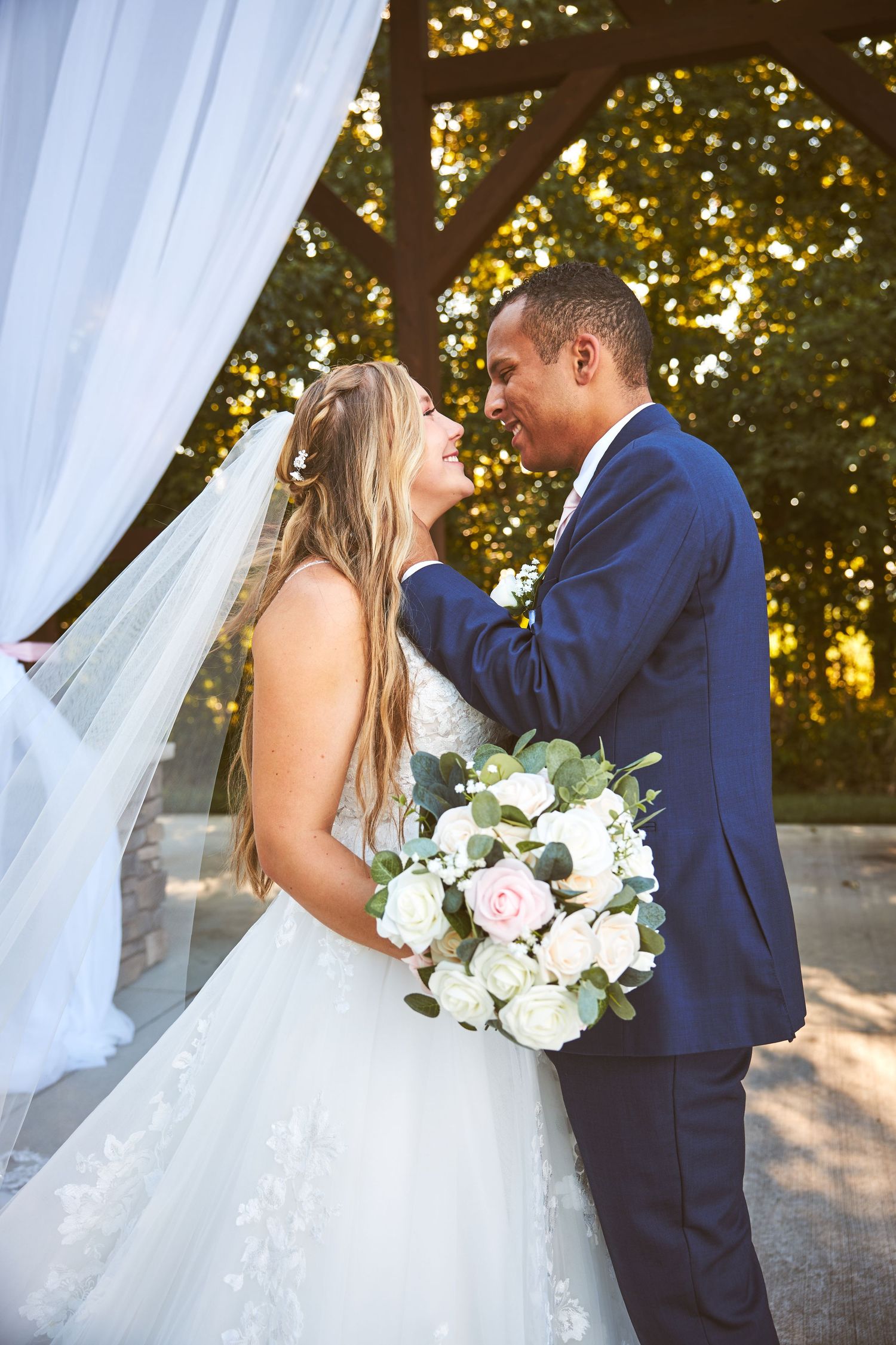 A couple shares intimate moments during their outdoor wedding photoshoot with white roses.