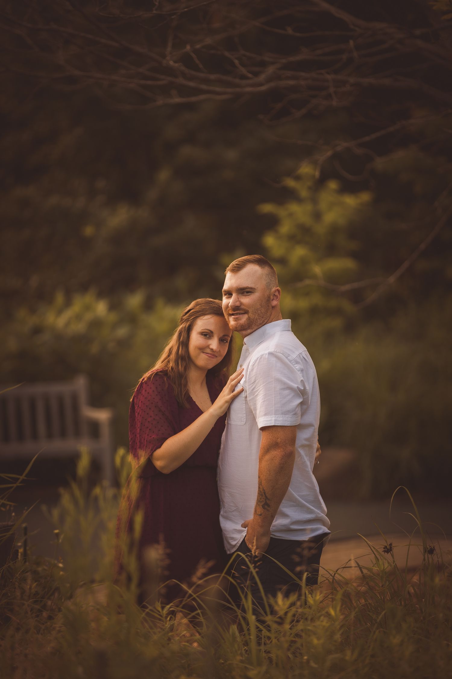 Two people share a tender moment in tall grass during golden hour.