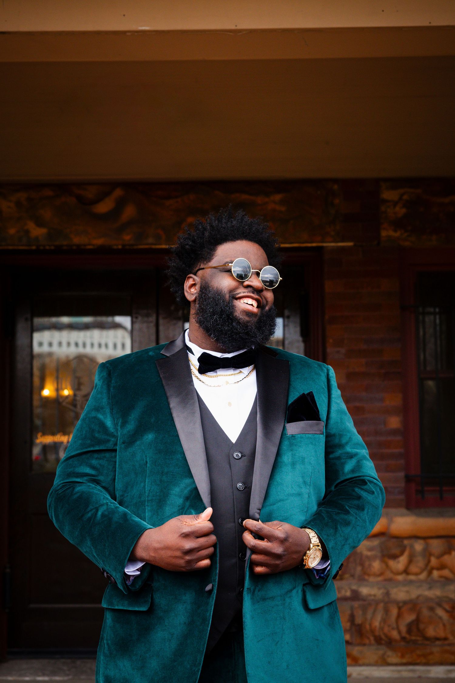 A stylish green velvet tuxedo jacket paired with a black vest and bow tie creates an elegant formal look.