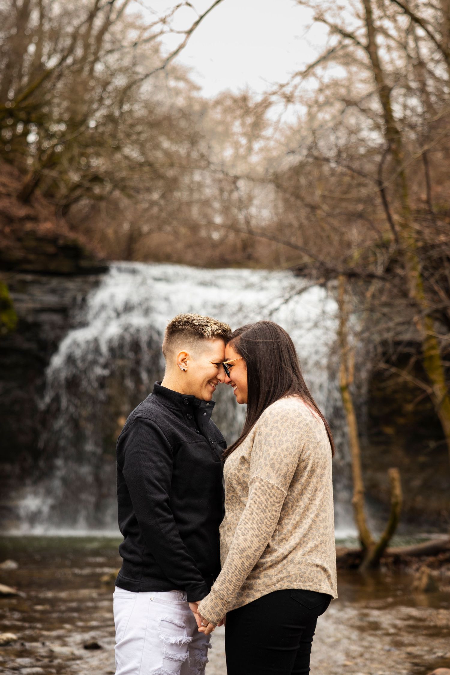 Intimate couple photoshoot in front of a scenic waterfall backdrop.