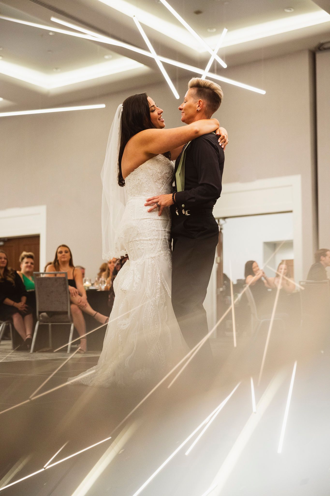 A first dance at a wedding reception with dramatic lighting and onlooking guests.
