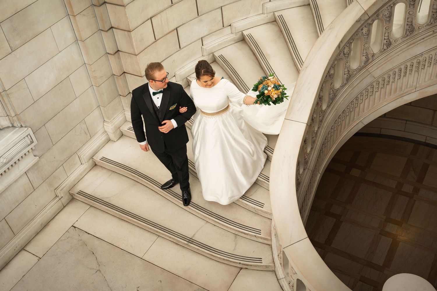 Panoramic wedding photos in a grand marble hallway with arched architecture.