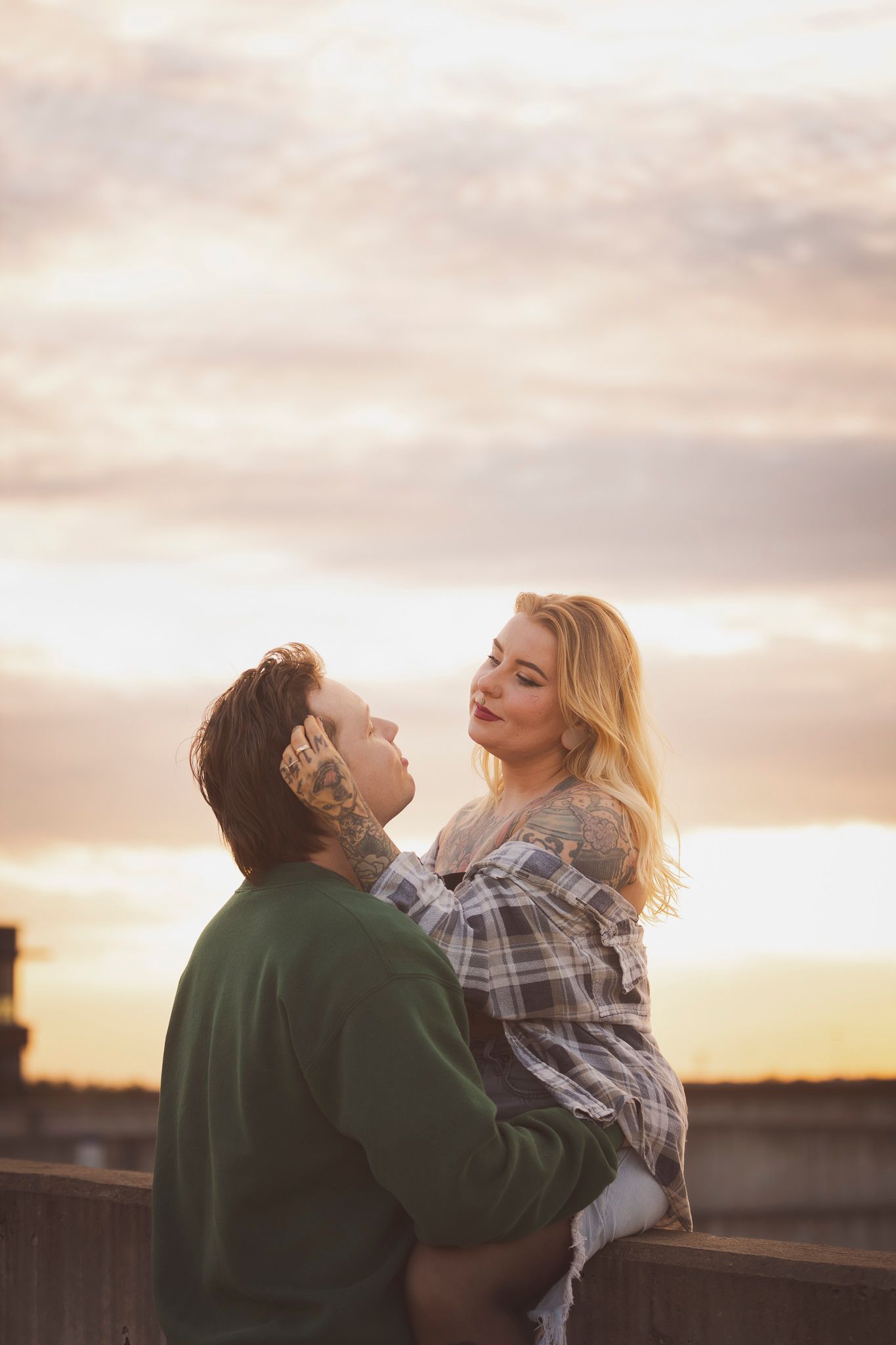 Couple embracing against sunset sky in casual attire.