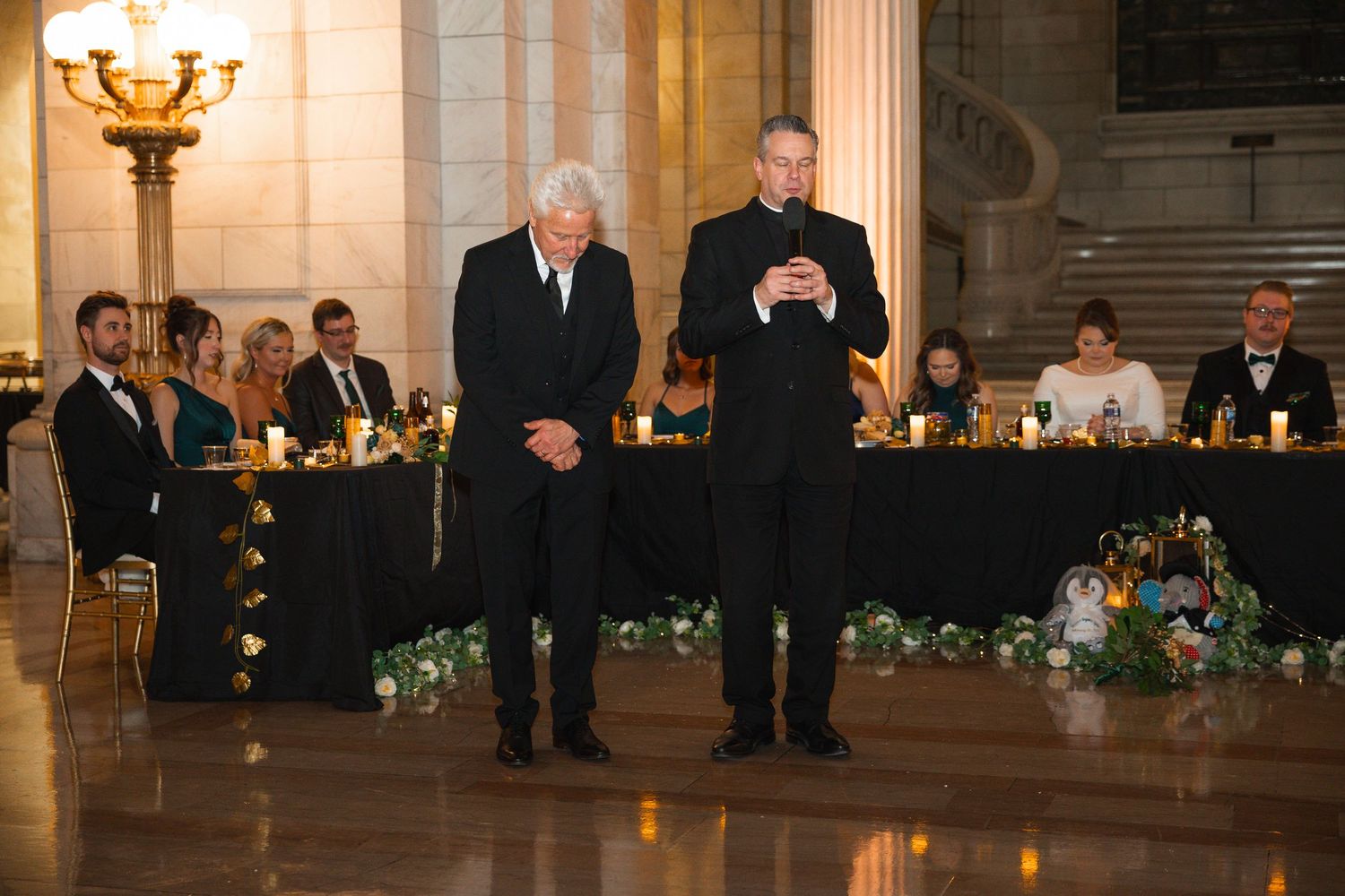 Elegant wedding reception hall with long tables adorned with floral centerpieces and warm lighting.
