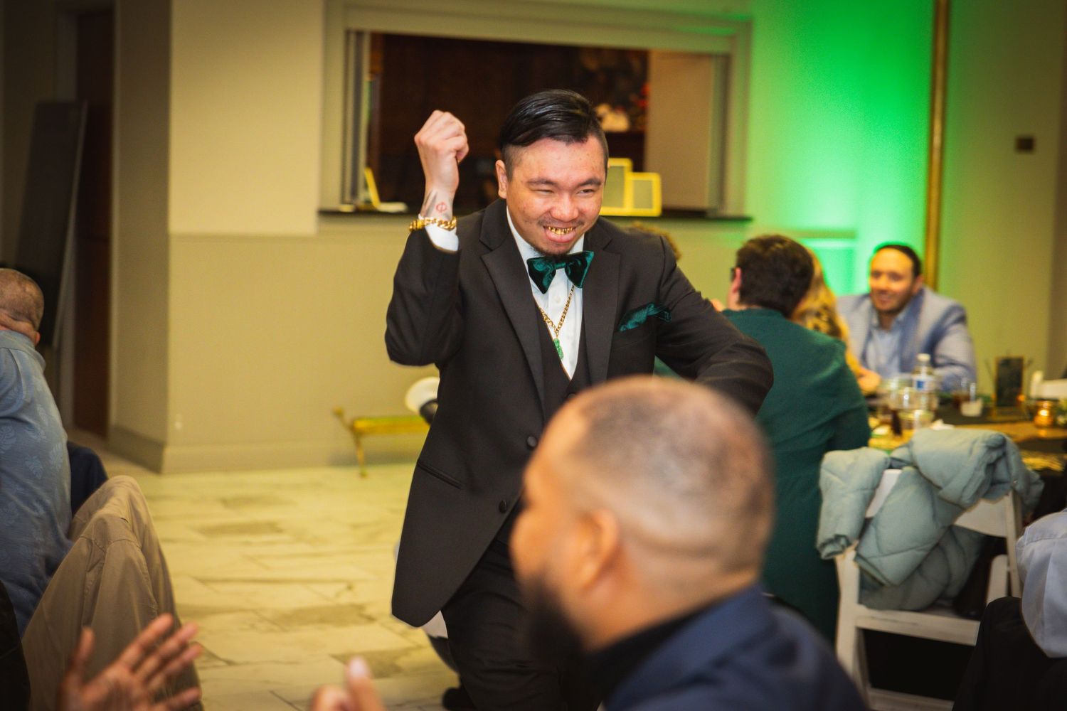 Celebratory atmosphere at a wedding reception with green accent lighting and formal attire.