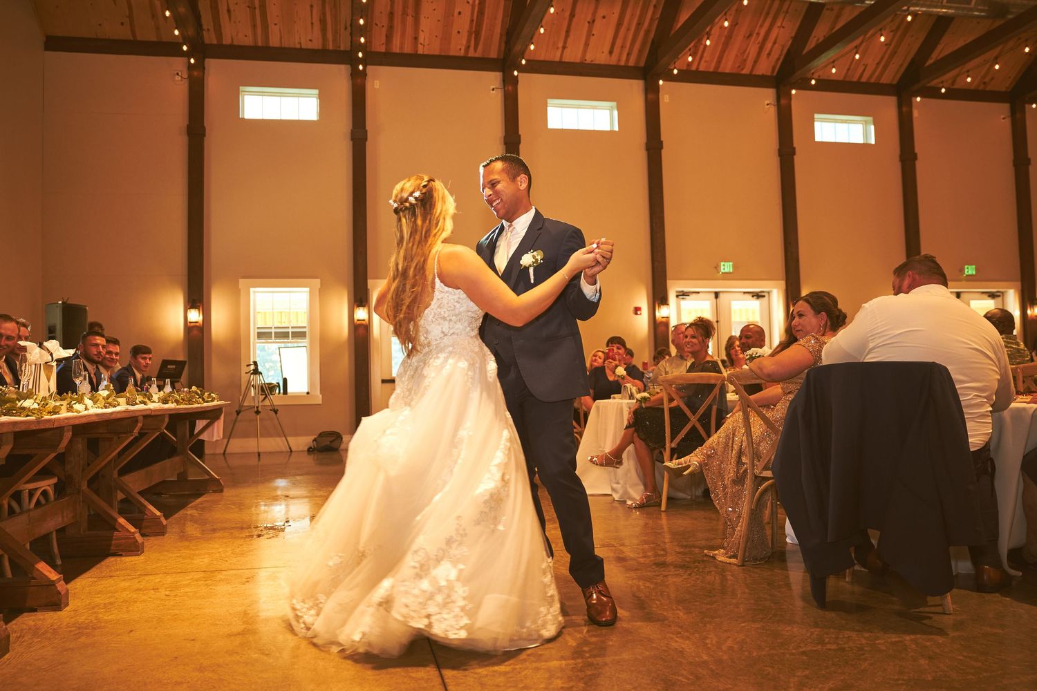 Spacious wedding reception hall with rustic decor and ambient lighting.