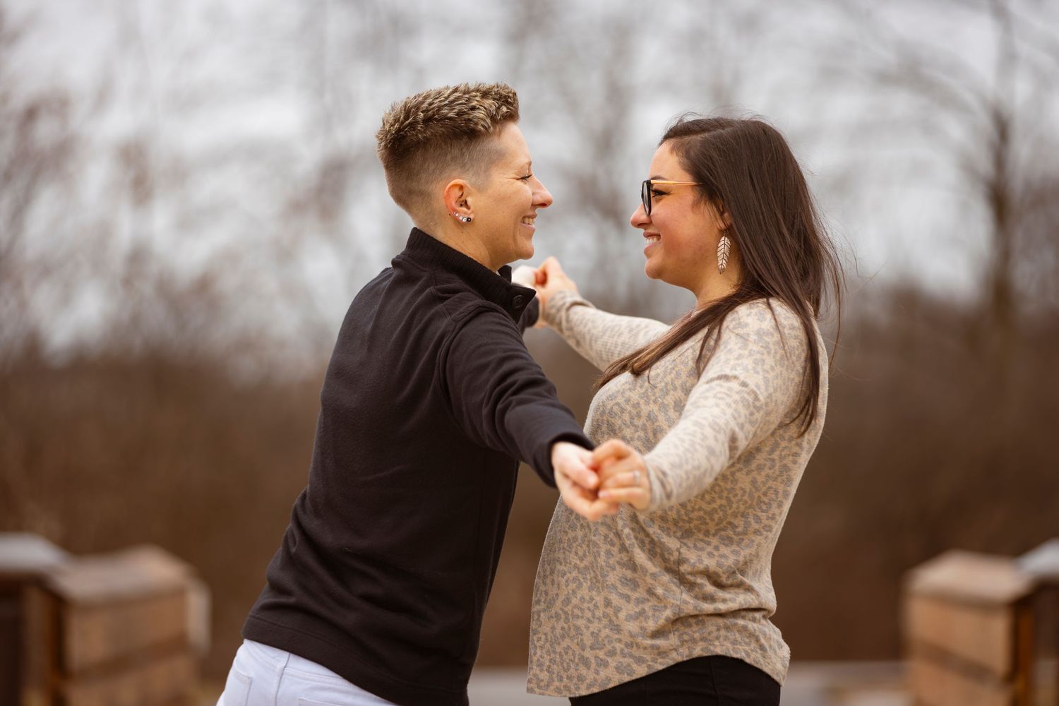 Playful couple photoshoot on a wooden bridge during winter.