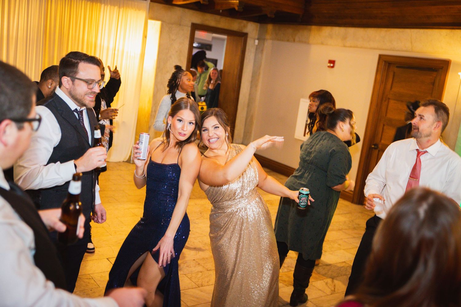 Wedding reception party with guests dancing and celebrating in a warmly lit venue.